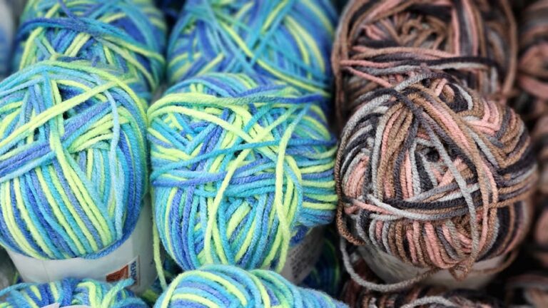 Colorful yarn balls arranged for a crochet bucket hat project showing soft DK weight wool in blue green and brown hues perfect for granny stitch colorwork