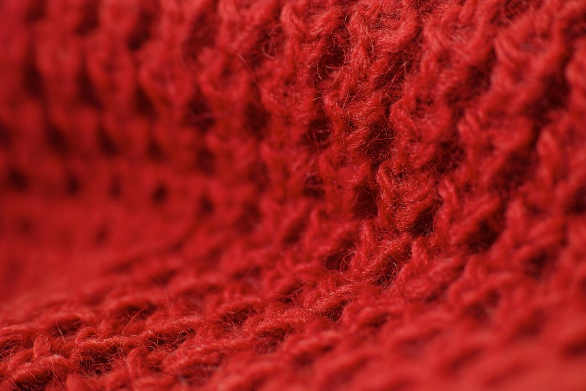 Close-up of red knitted wool fabric showing crochet stitch texture for handmade Mother Day gifts