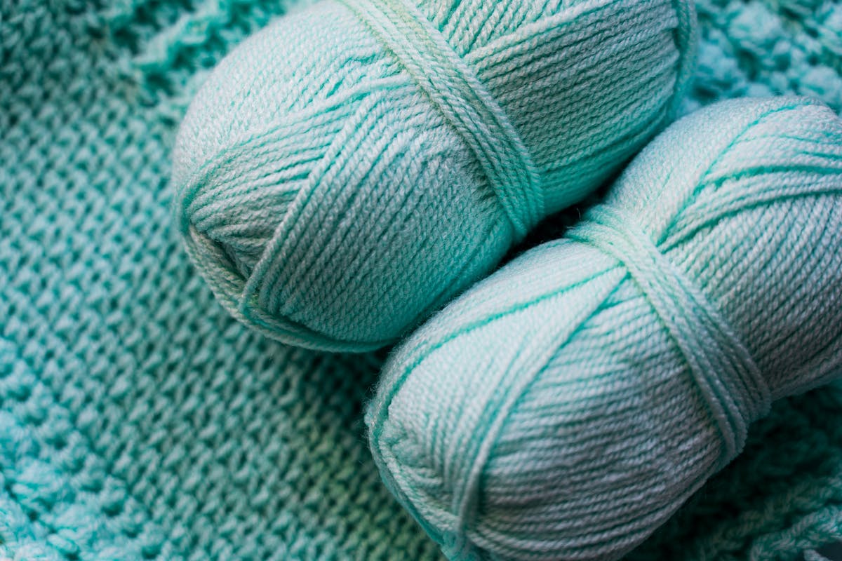 Teal yarn balls on knitted textile background for crochet vest inspiration