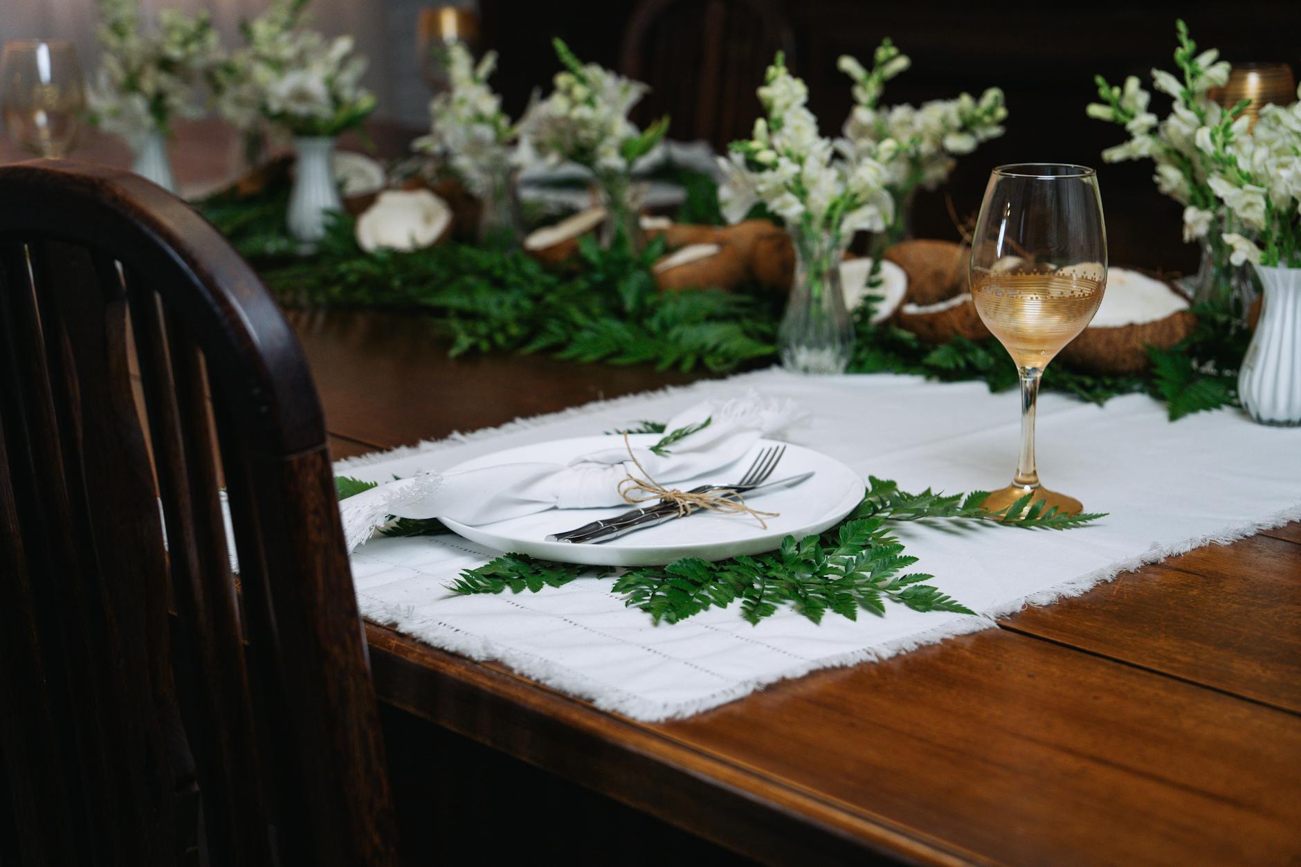crochet table runner patterns - Sophisticated dining setup with wine glass, plate, and floral arrangements on a wooden table.