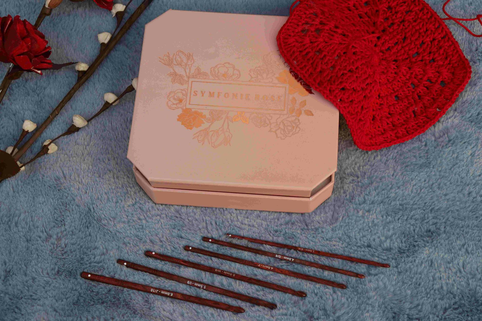 this technique - Flat lay of crochet set with hooks, red doily, and decorative box on fabric.
