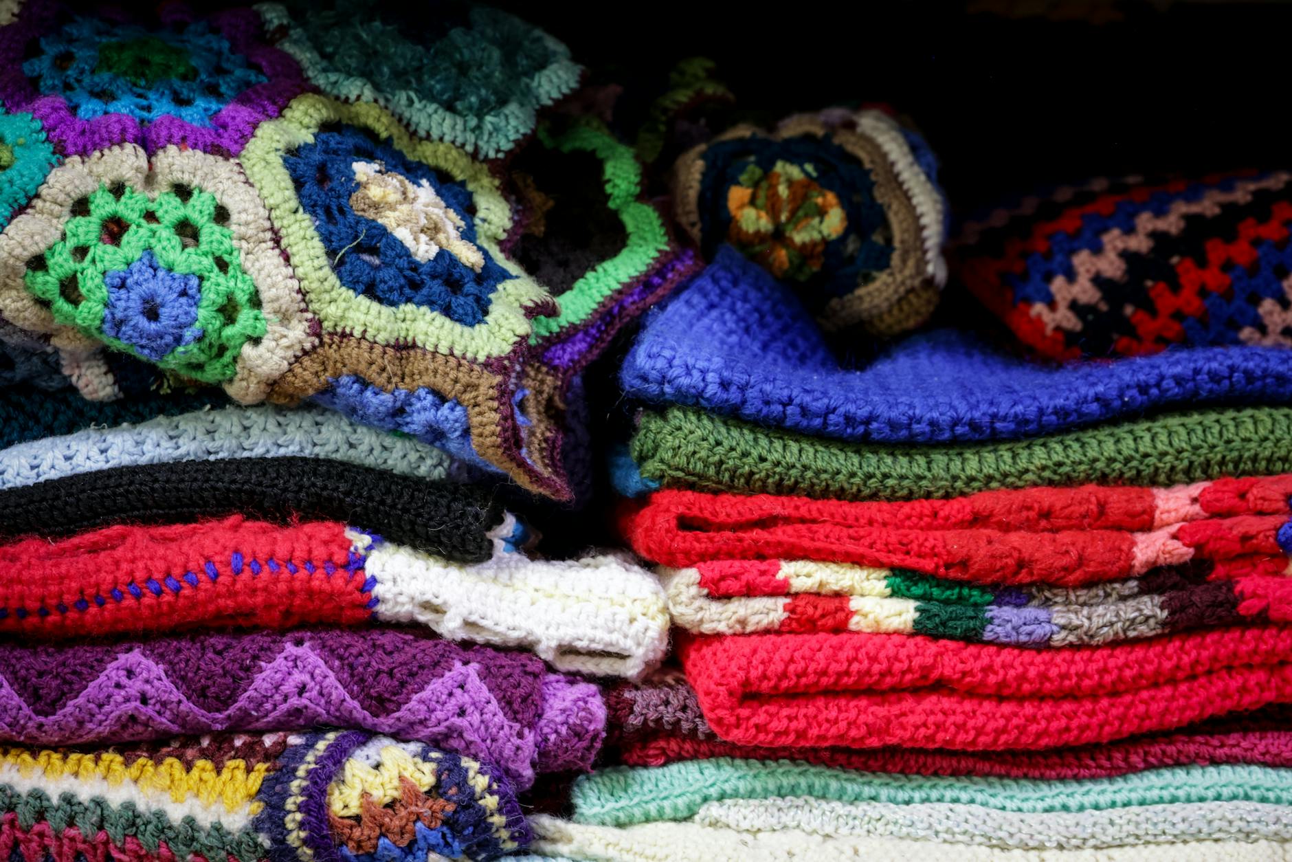 corner to corner crochet - A vibrant stack of vintage crochet blankets showcasing intricate patterns and colorful designs.