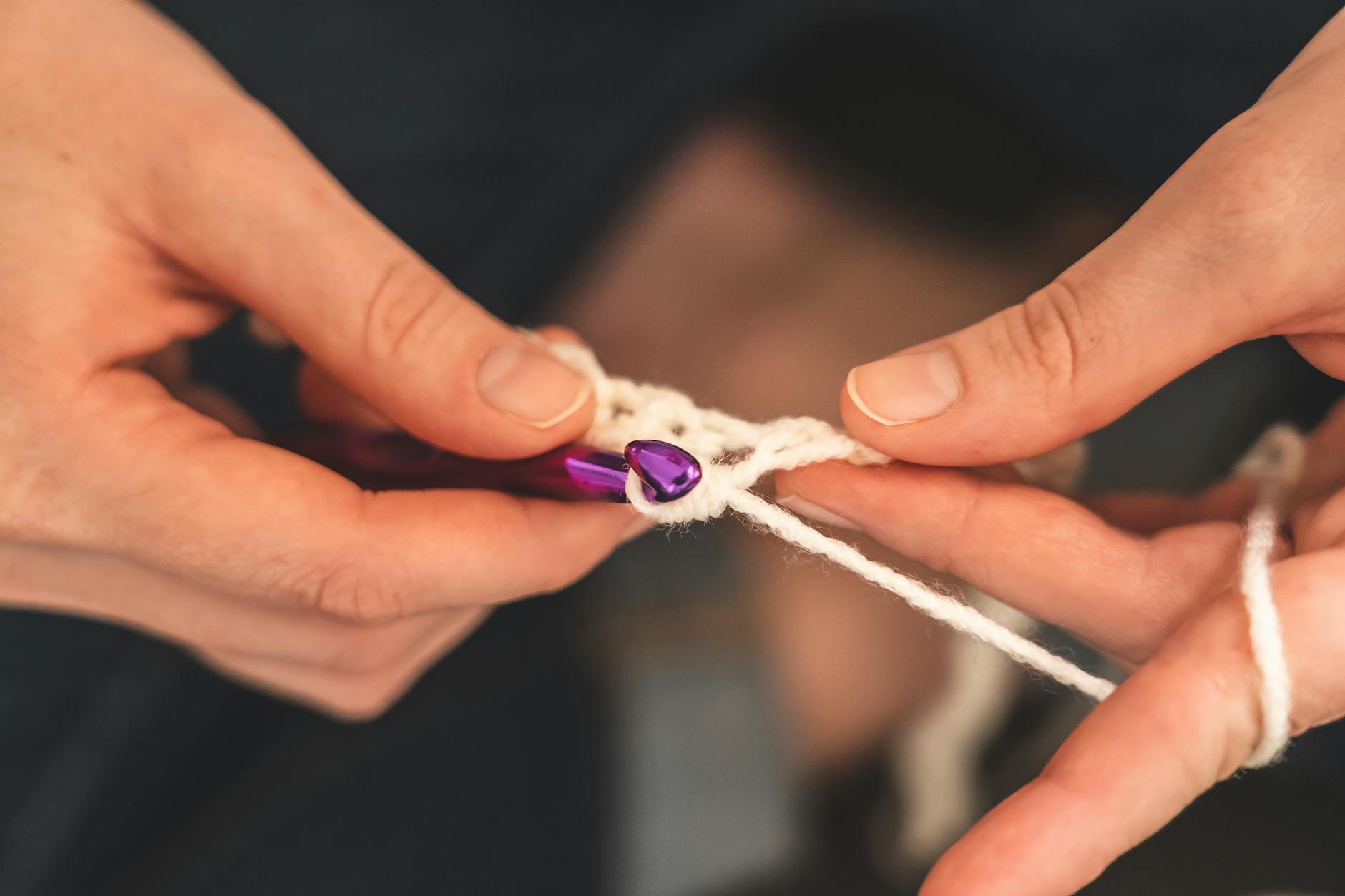 guide - Detailed view of hands skillfully crocheting with a purple hook, featuring soft yarn and intri