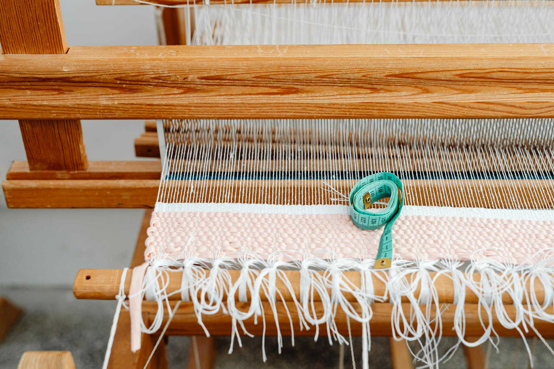 crochet table runner patterns - Close-up of a wooden loom with yarn and a green tape measure, showcasing traditional weavi...