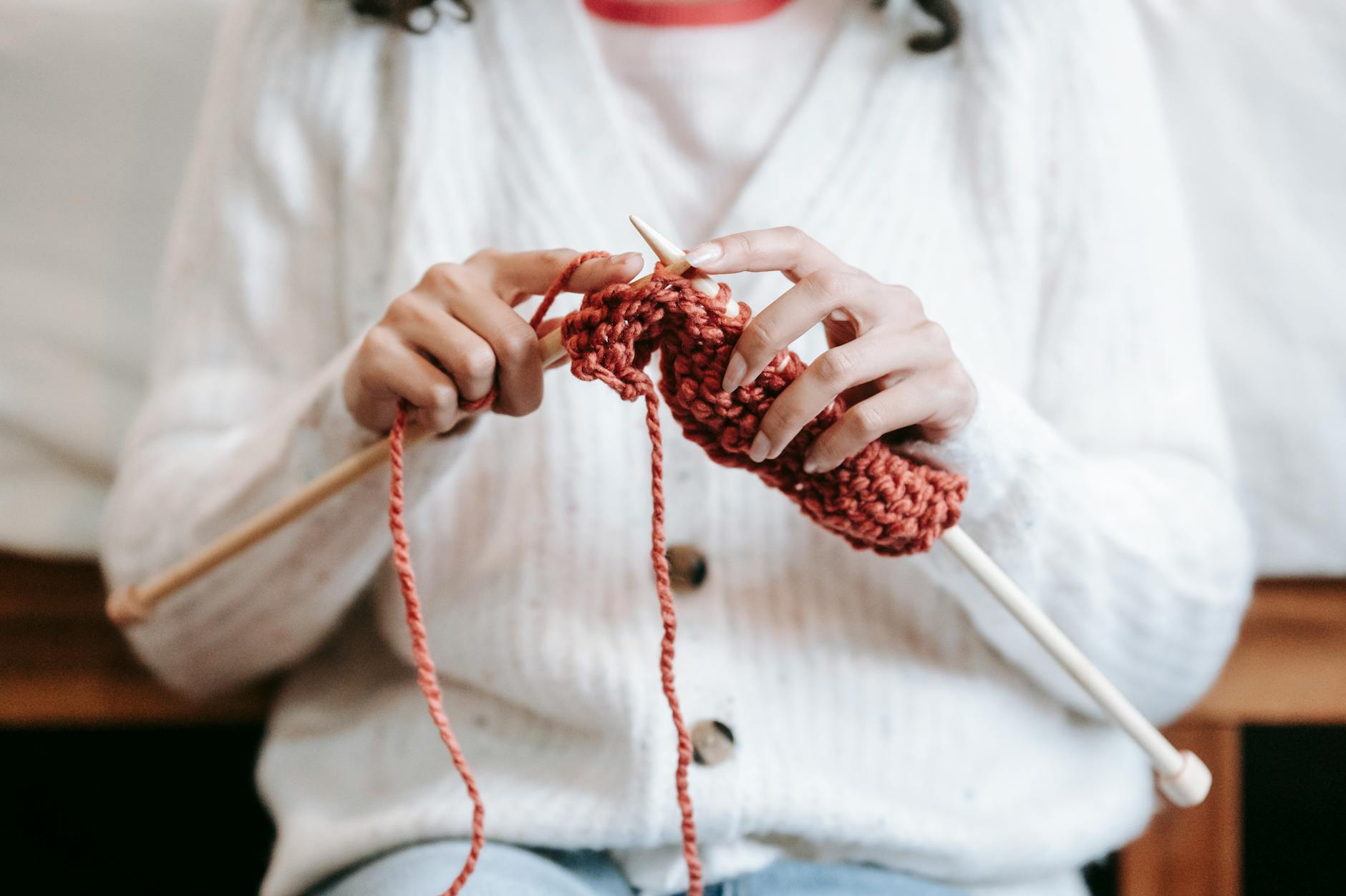 granny square cardigan patterns - Crop unrecognizable female wearing warm woolen cardigan sitting on chair and knitting with 