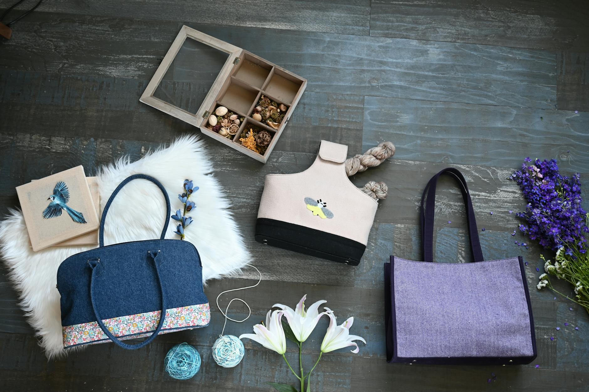 crochet handbag patterns guide - A collection of bags, floral designs, and accessories arranged on a wooden surface for a sty