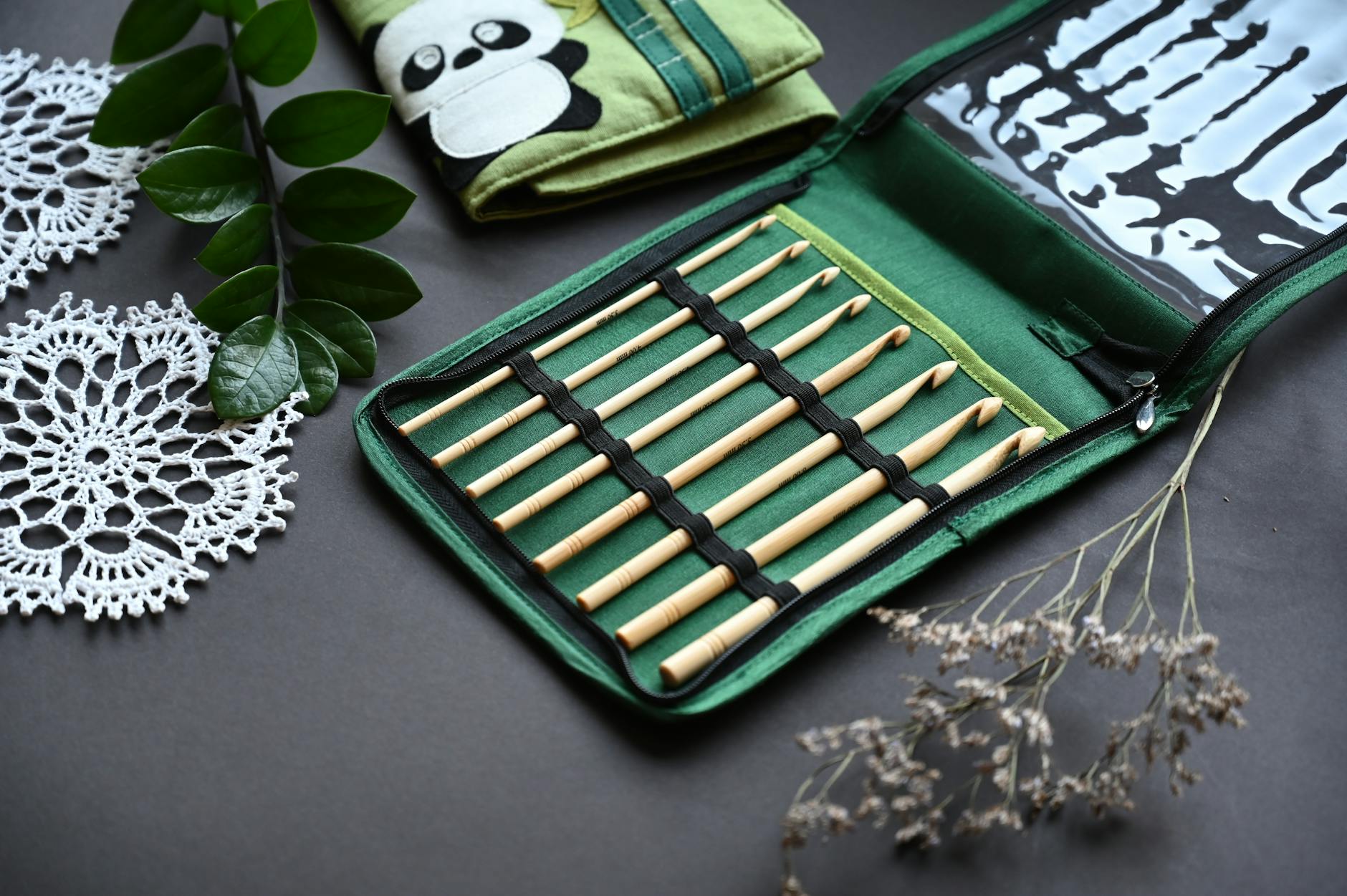 crochet phone case pattern guide - Stylish bamboo knitting needles in a green case with crochet doilies and leaves, perfect f