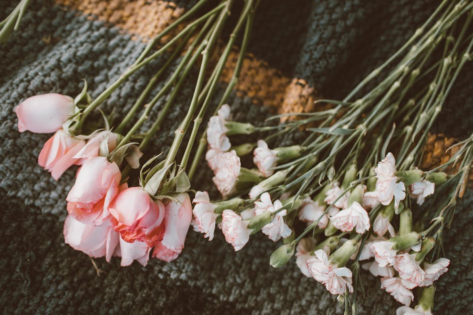 Aesthetic display of pink roses and carnations on textured knit fabric perfect for floral crafting
