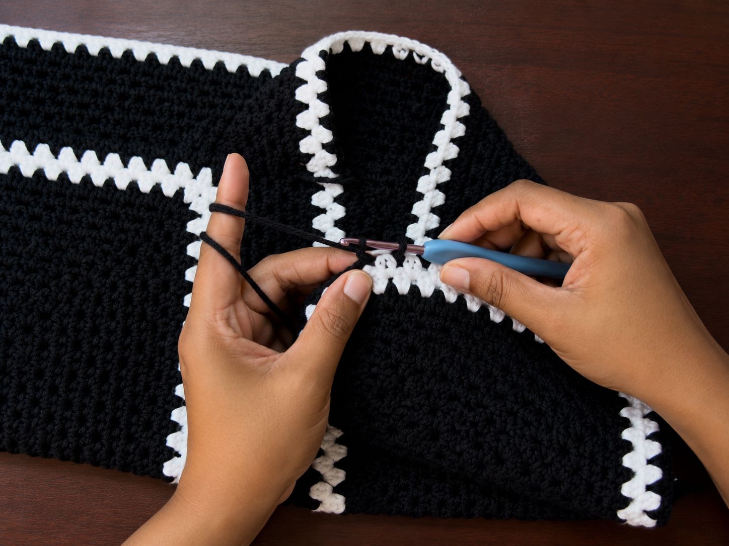 Stitching along the white bordered edge of a crochet hexagon shirt for collar finishing