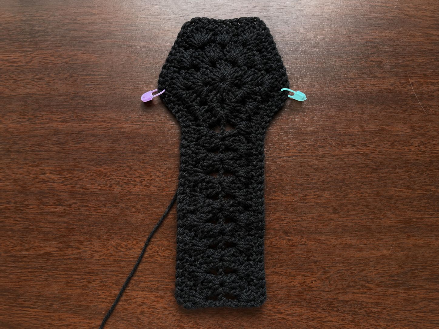Black hexagon crochet piece with stitch markers for shirt construction