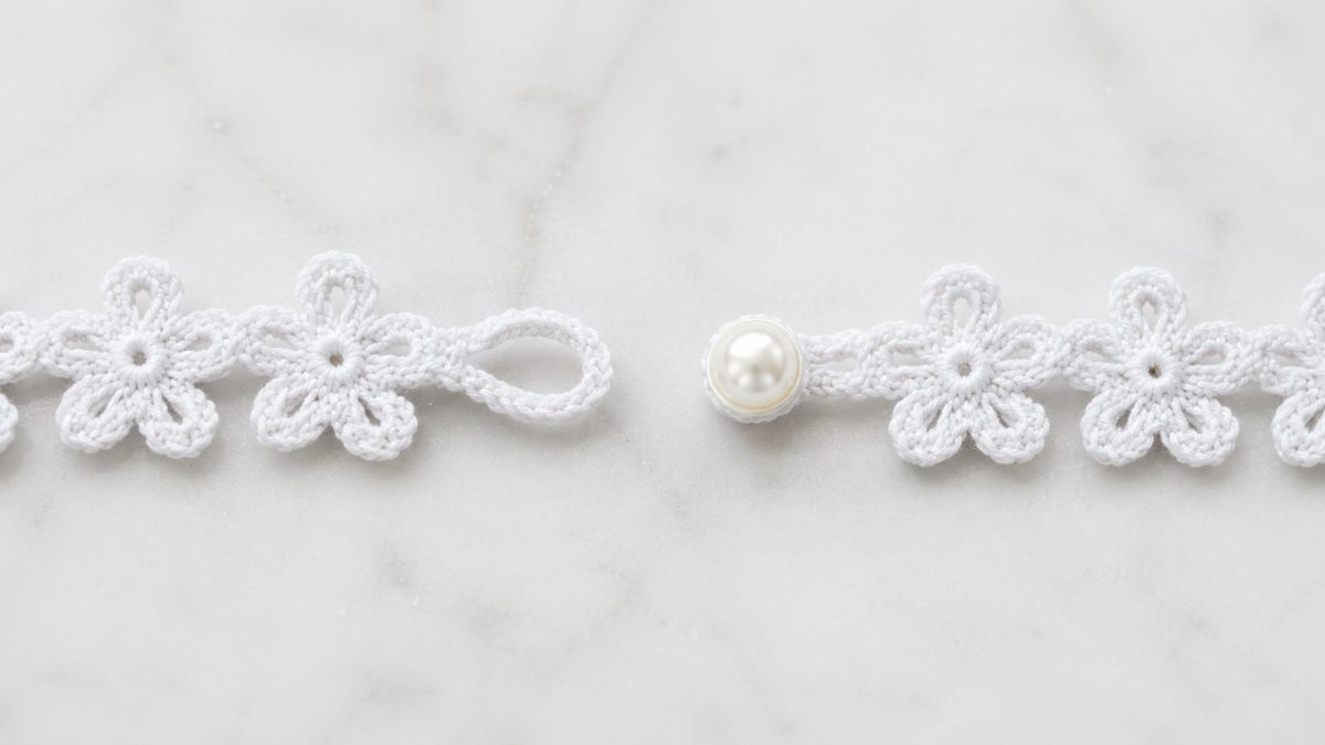 Button and chain loop closure detail on the finished crochet flower bracelet