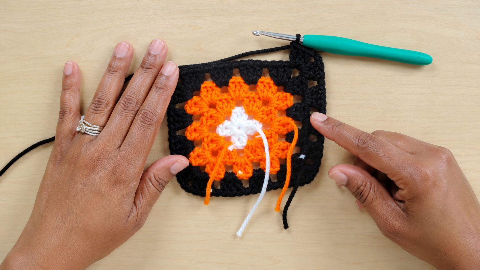 Crocheting a black orange and white granny square in progress