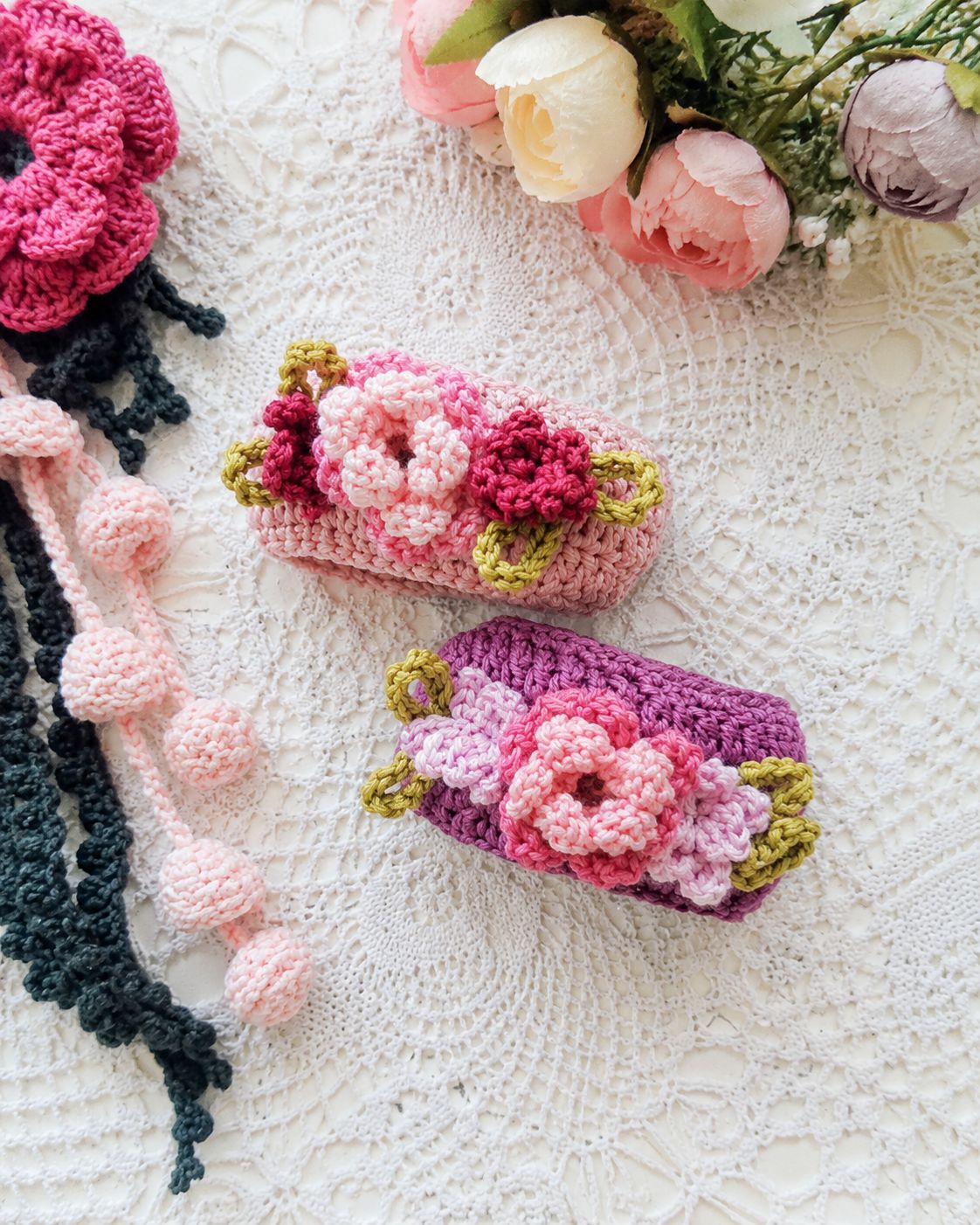 Two rectangular crochet bangles with pink purple bases adorned with 3D floral motifs and yellow accents
