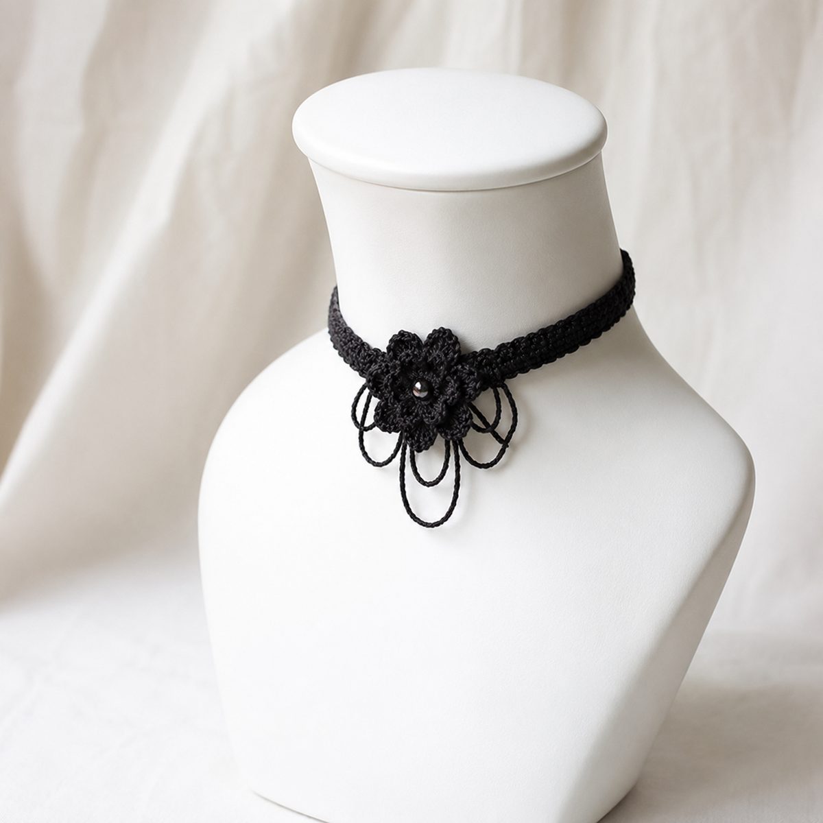 Black crochet choker with a flower centerpiece and loop dangles on a bust