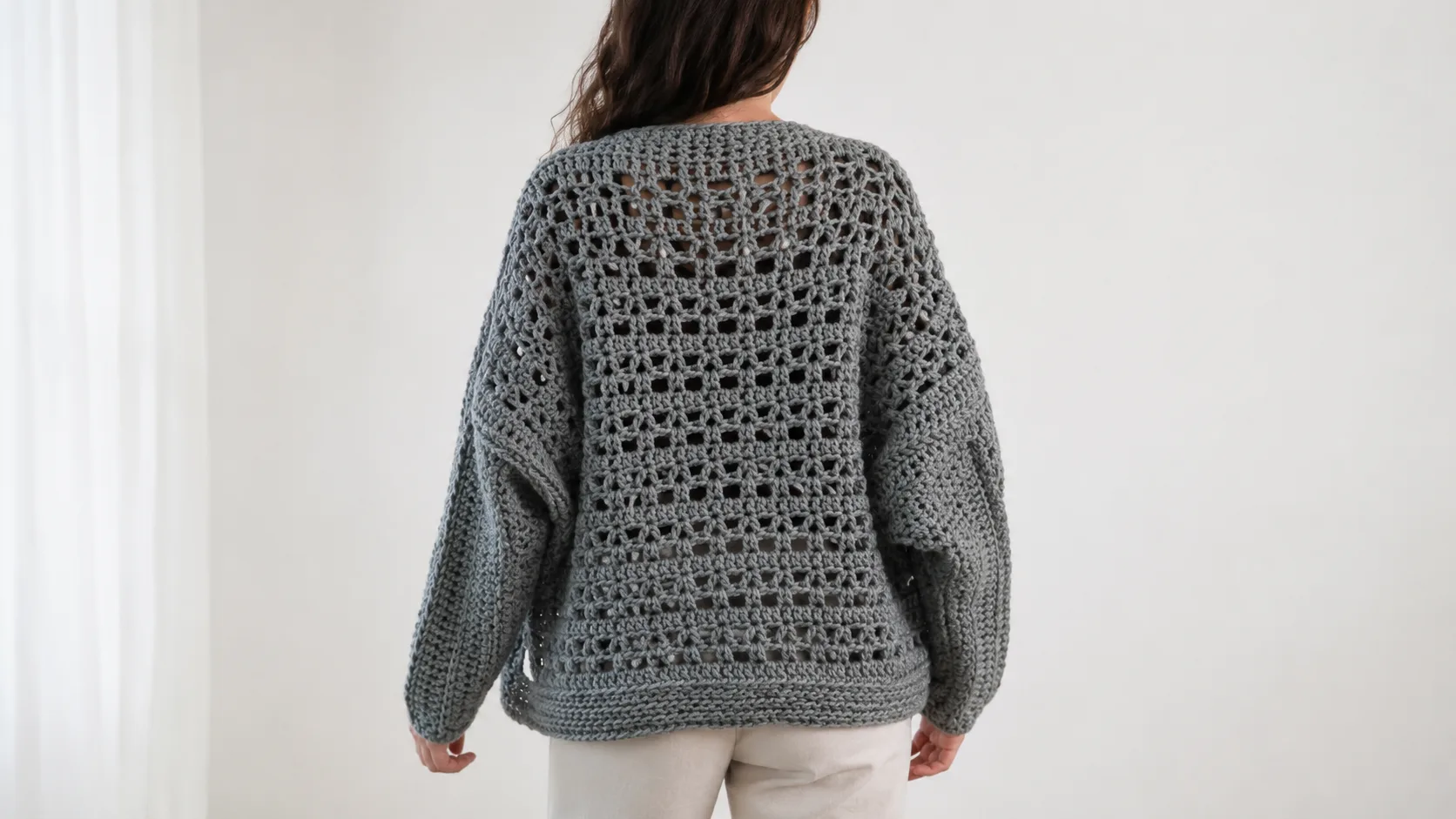 Adult wearing a gray handmade crochet bolero with a lacy back panel
