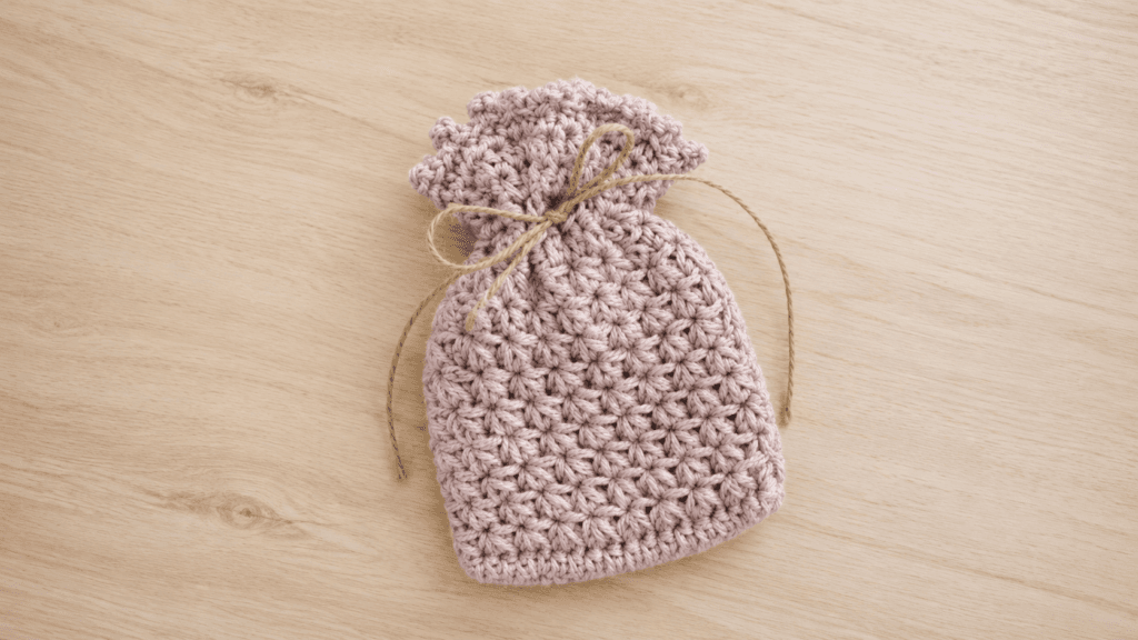 Dusty blush crochet drawstring pouch with a tan twine bow