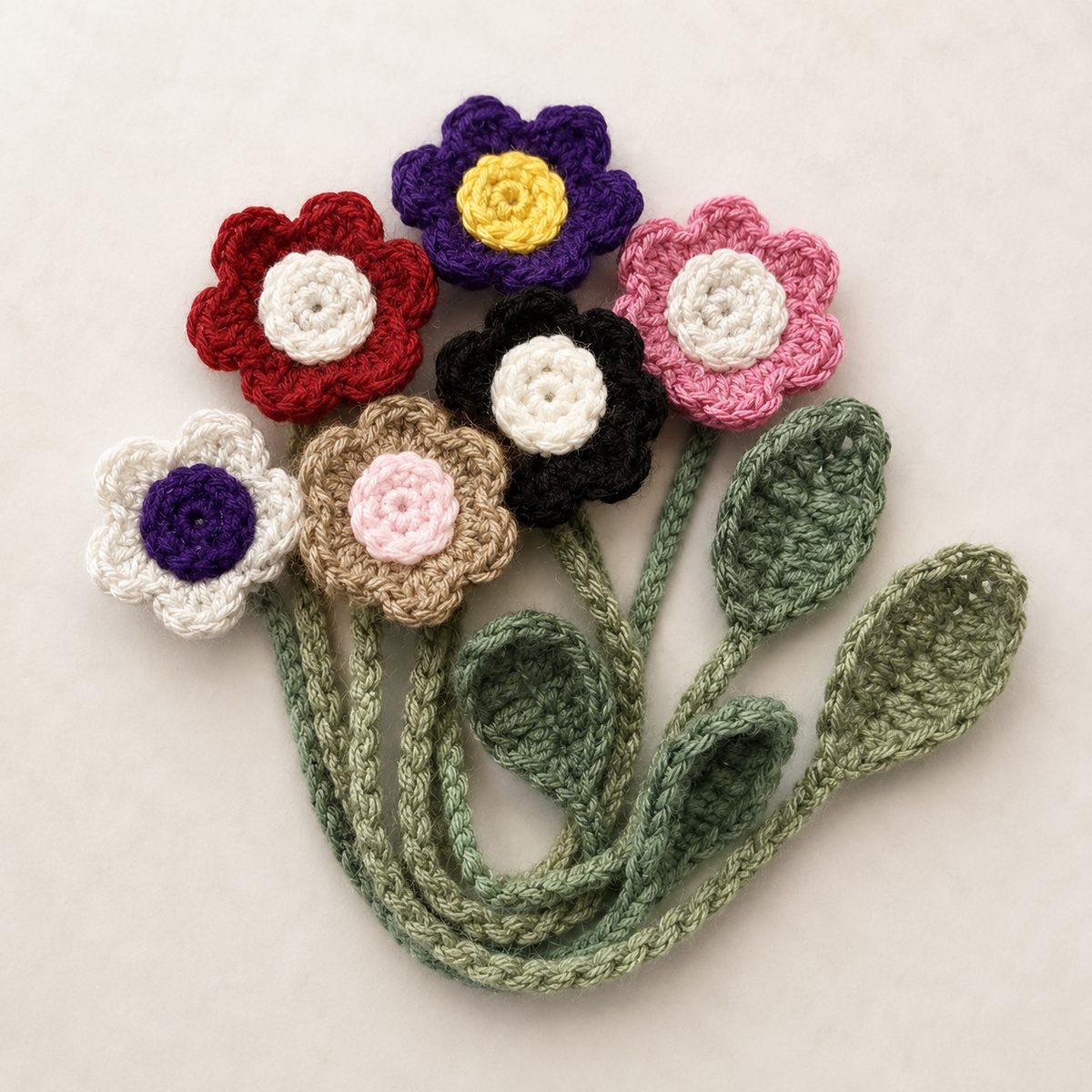 Bouquet of crochet flower bookmarks with braided green stems and leaves, flowers in red, purple, pink, black and cream