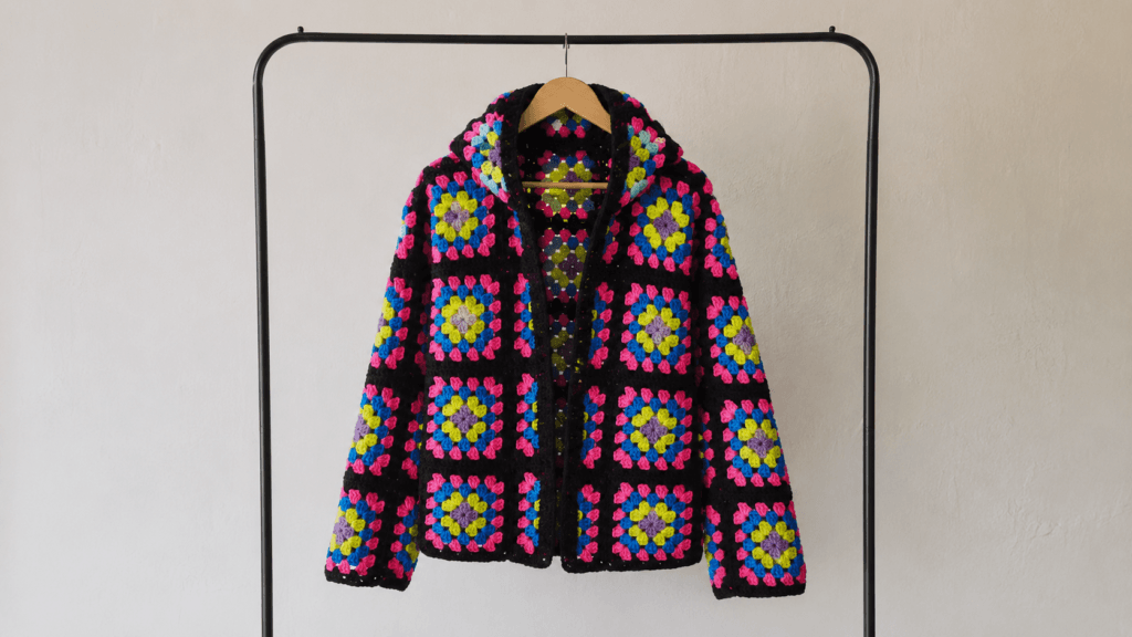 Black hooded crochet cardigan assembled from bright floral granny squares