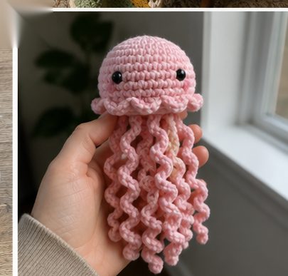 Small handmade amigurumi crochet jellyfish in pink cotton with safety eyes and long curly tentacles held in an open hand near a window