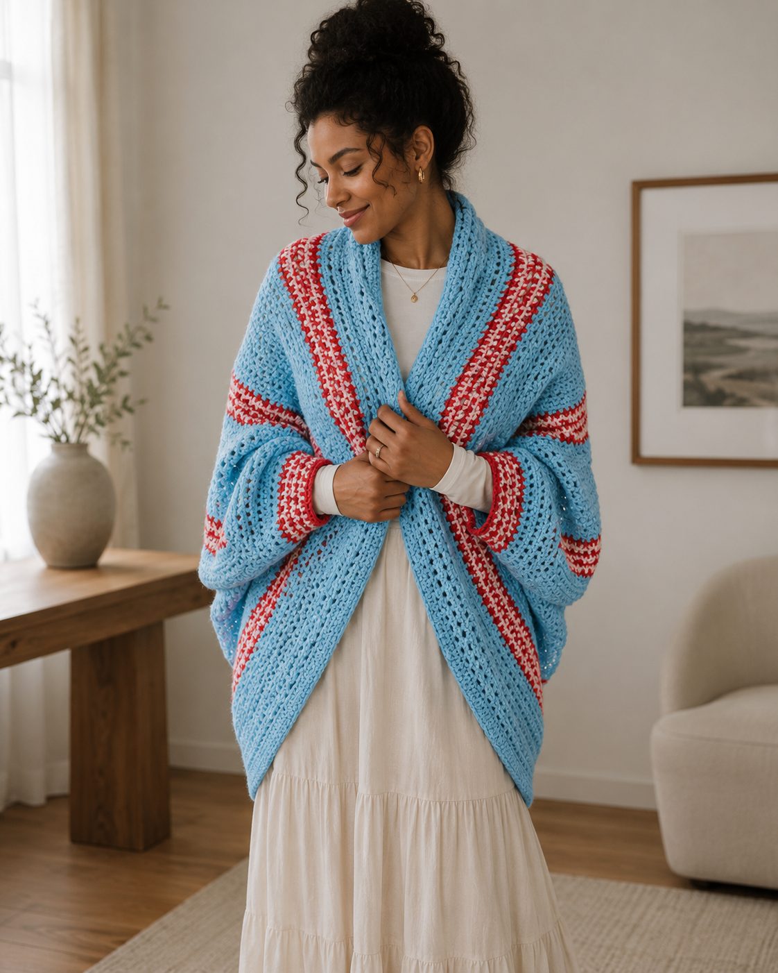 Light blue crochet shrug with red and white colourwork bands wrapped at the front