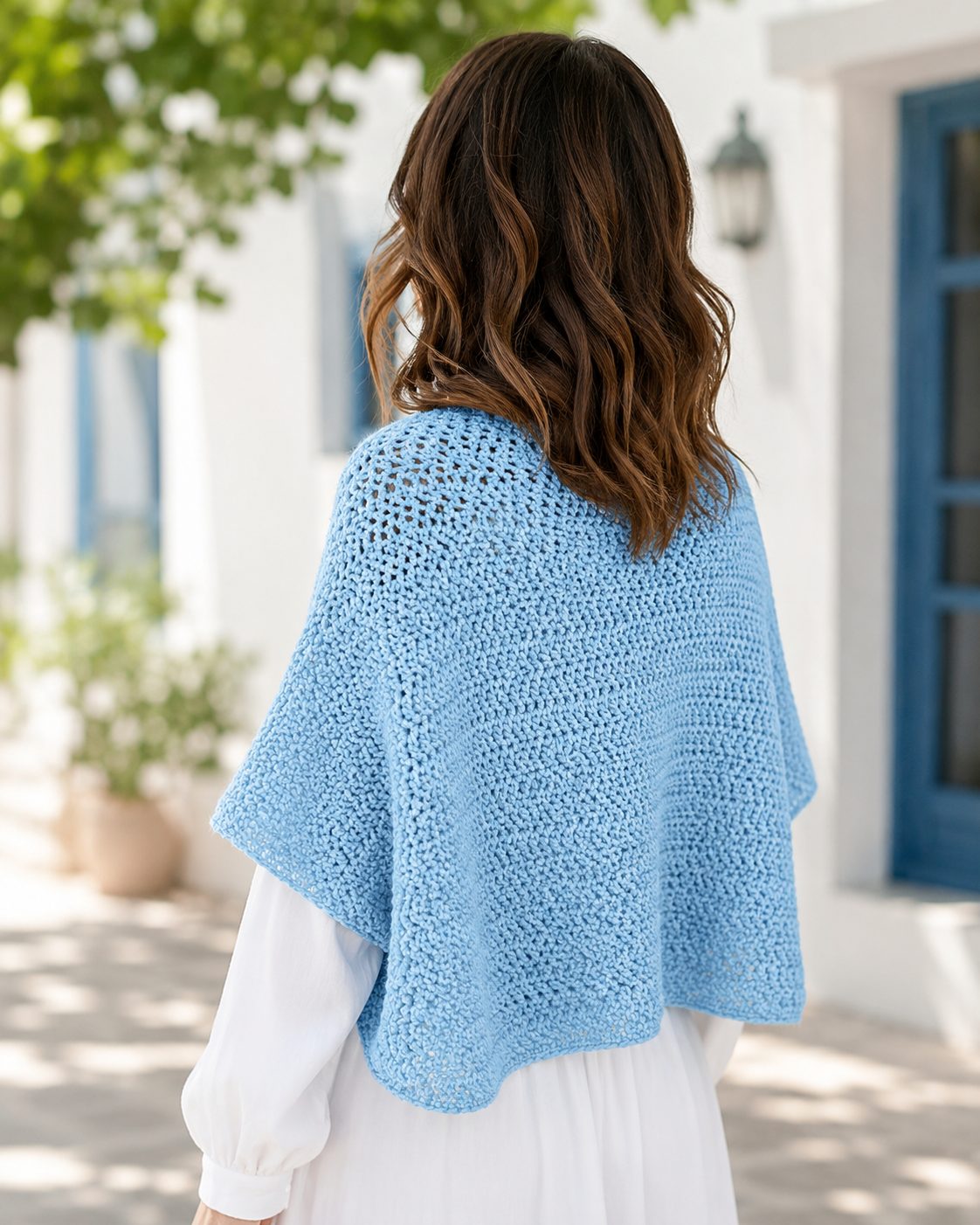 Simple light blue crochet shrug seen from the back with a soft textured fabric