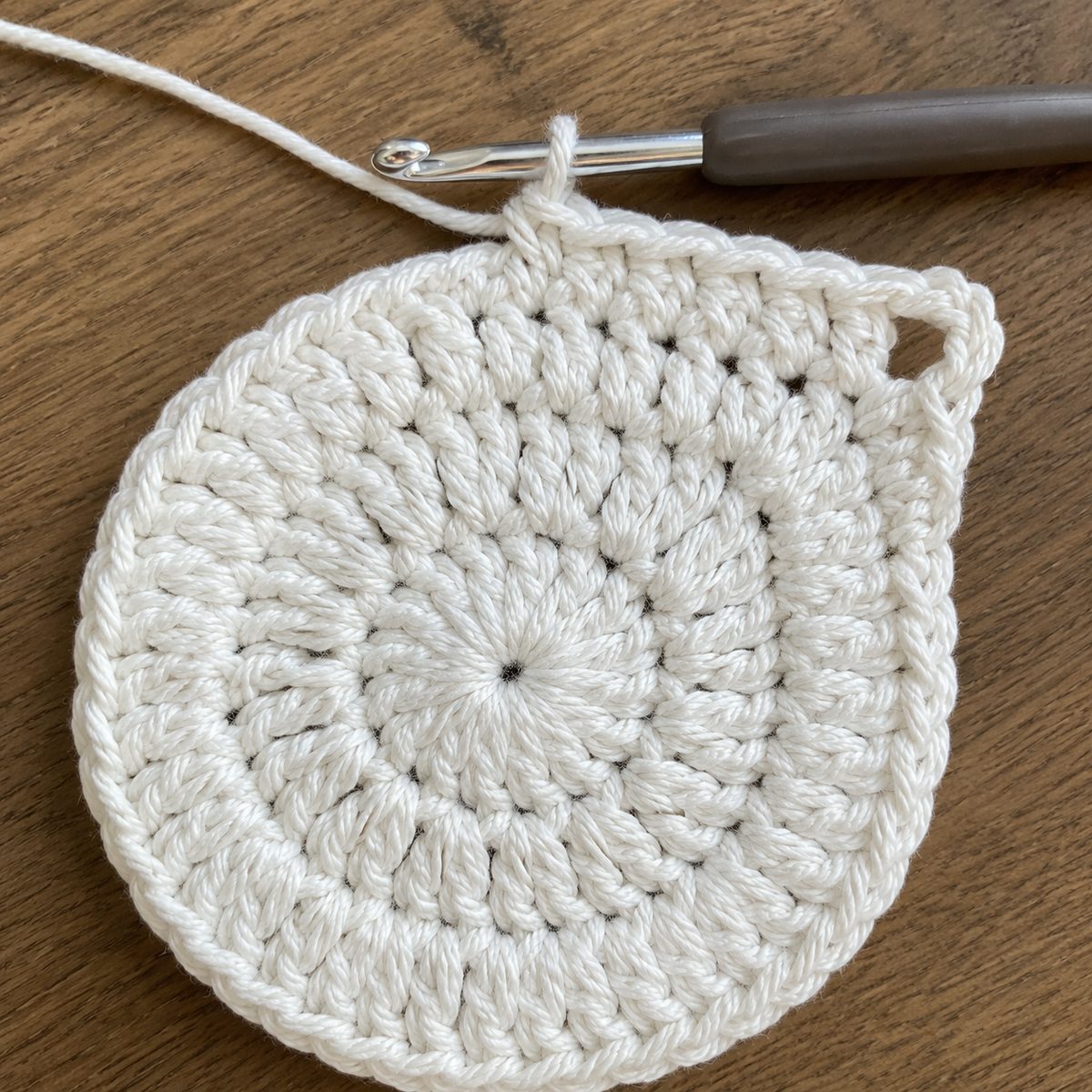 White crochet circle being squared with a corner chain space, worked into back loops