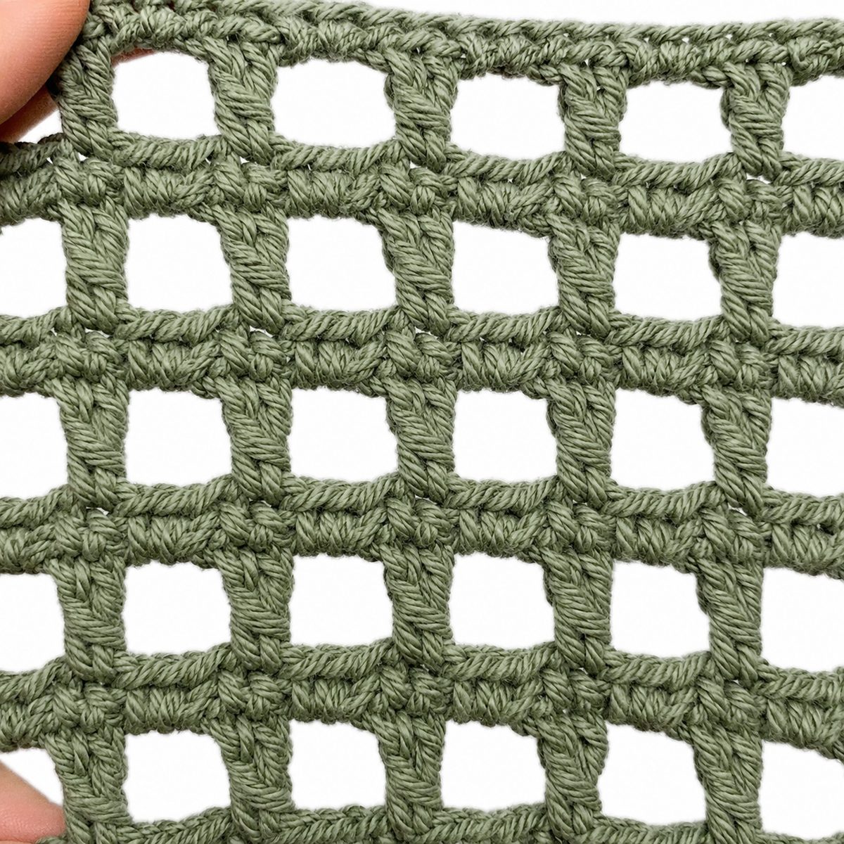 Close up of the square mesh grid held between fingers, one dc post and one chain space per box