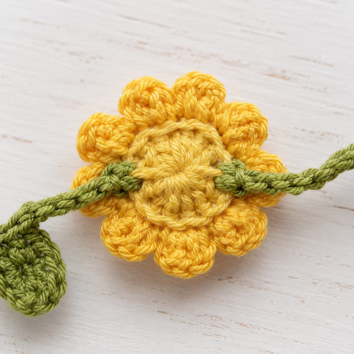 Back of a crochet sunflower showing the green band entering one side and exiting the other