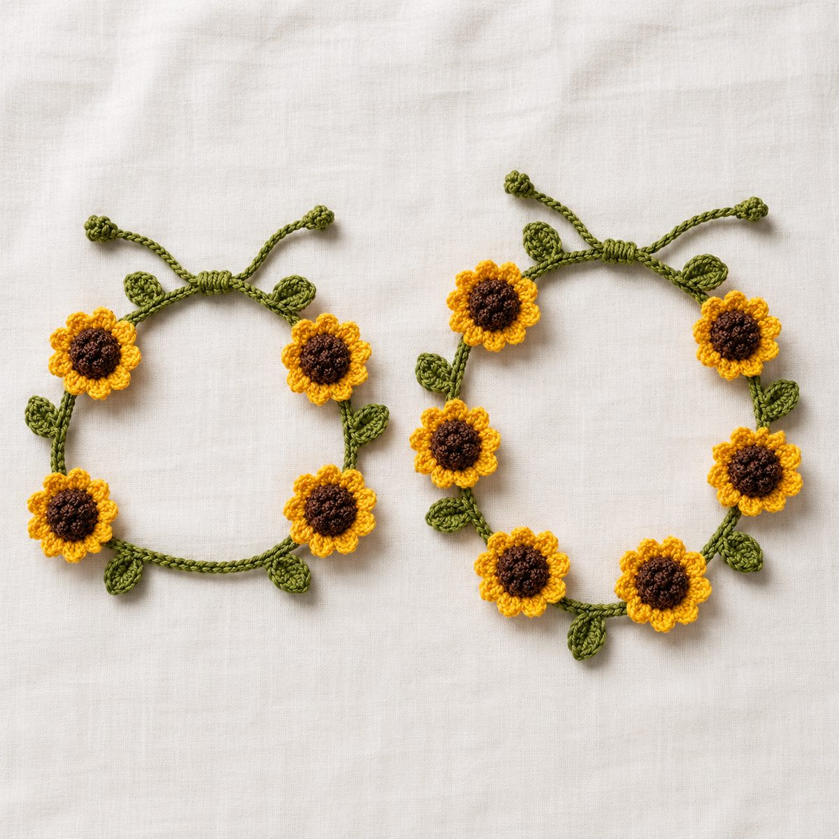 Two crochet sunflower bracelets side by side, a four flower size and a six flower size, on white fabric
