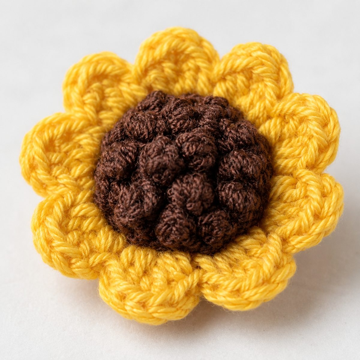Close-up of a finished crochet sunflower with bumpy brown popcorn center and broad ruffled yellow petals