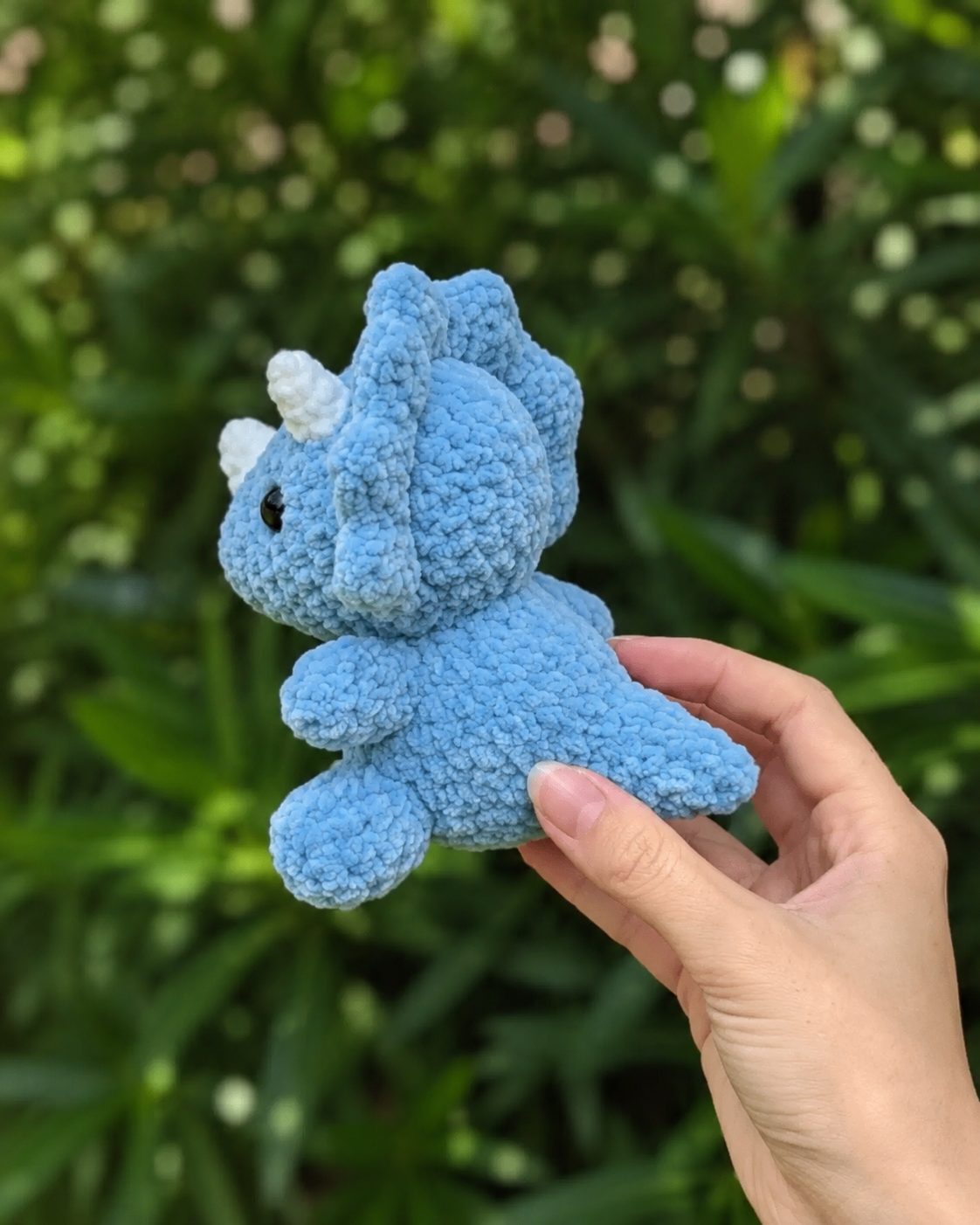 Back view of the blue amigurumi triceratops showing the crocheted-on rounded frill and tail