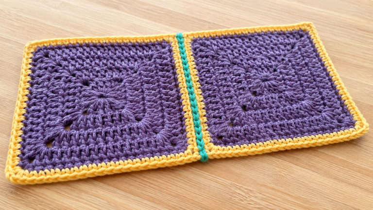 Two purple crochet granny squares joined with a turquoise seam