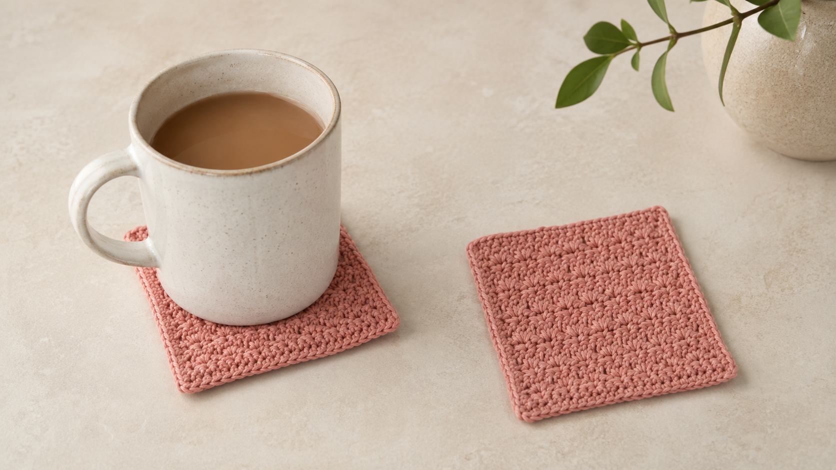 Pink square crochet coasters with a mug