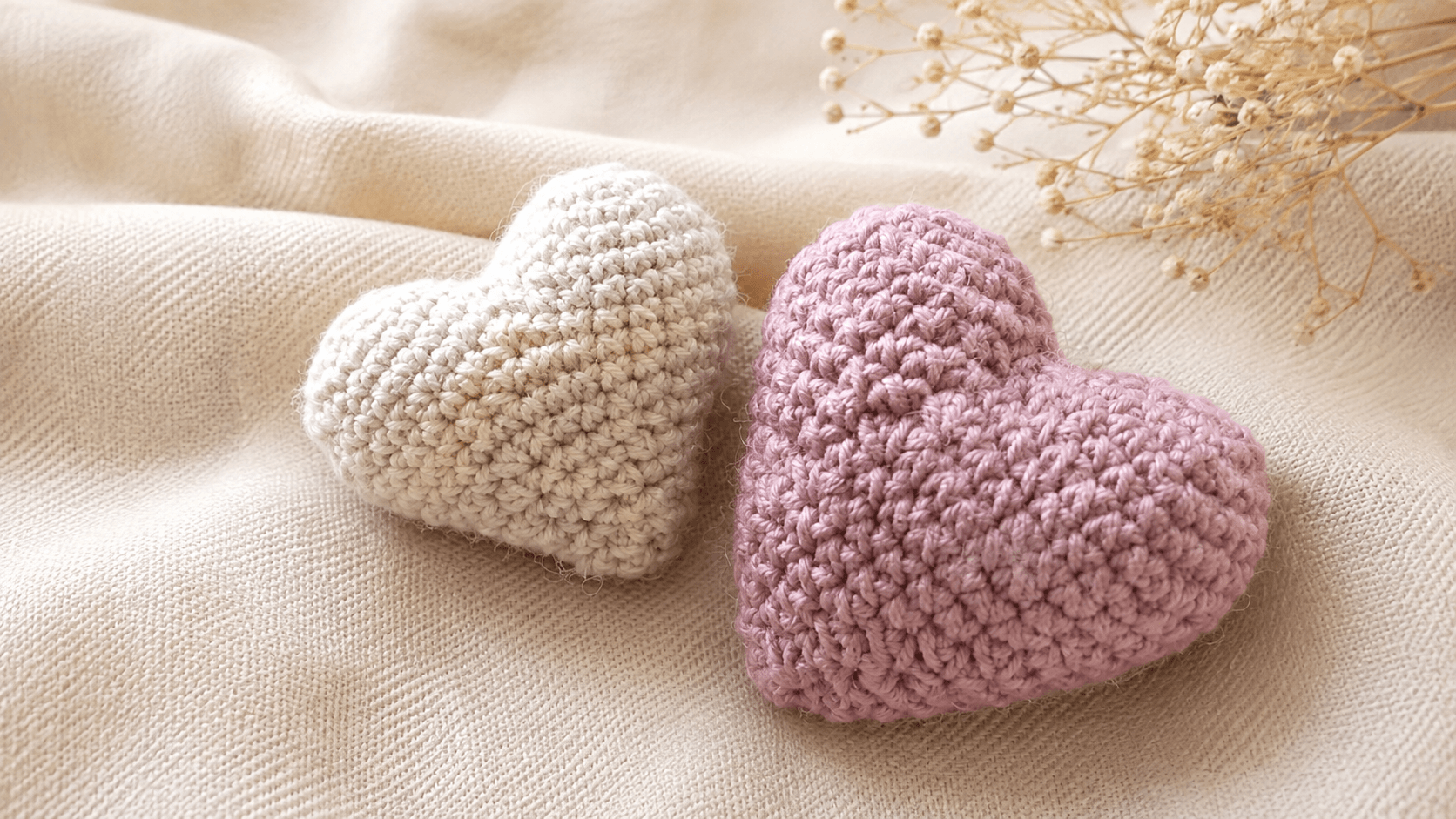 Hand holding two puffy white and lavender crochet hearts