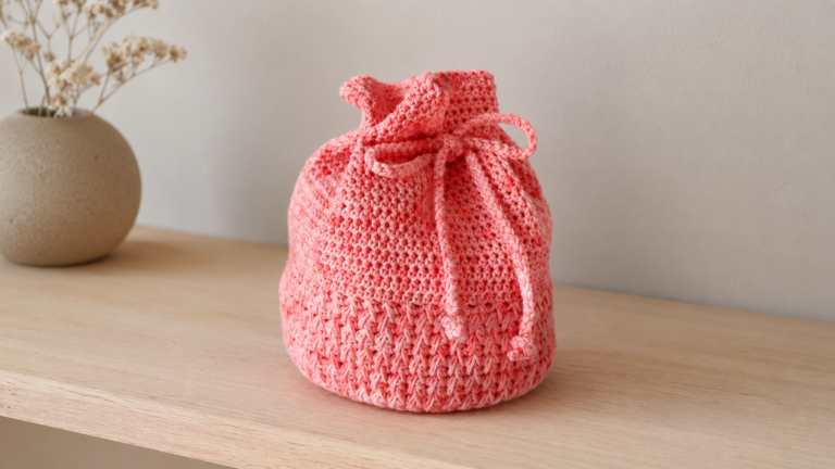 Pink crocheted drawstring bag on a shelf
