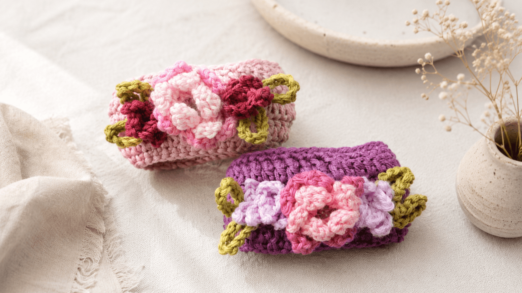 Two small oval crochet bangles with pink 3D flower clusters and green leaf accents