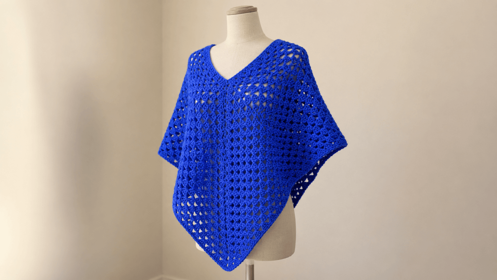 Solid royal blue crochet granny square poncho, outdoors, back view