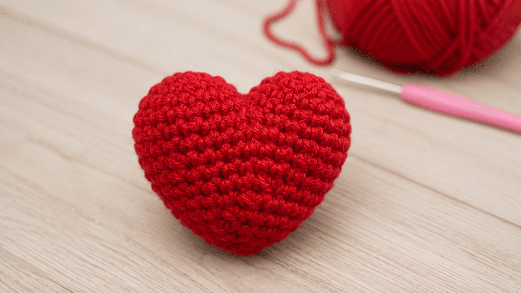 Hand holding a single red amigurumi crochet heart