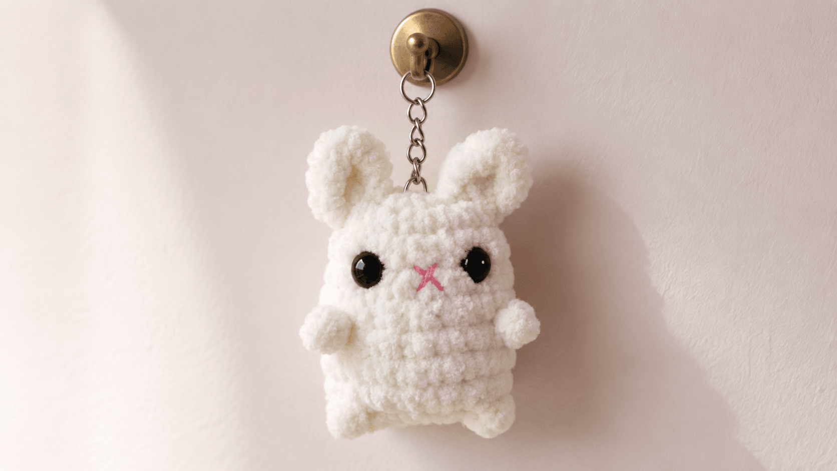 White crochet bunny keychain hanging on a hook