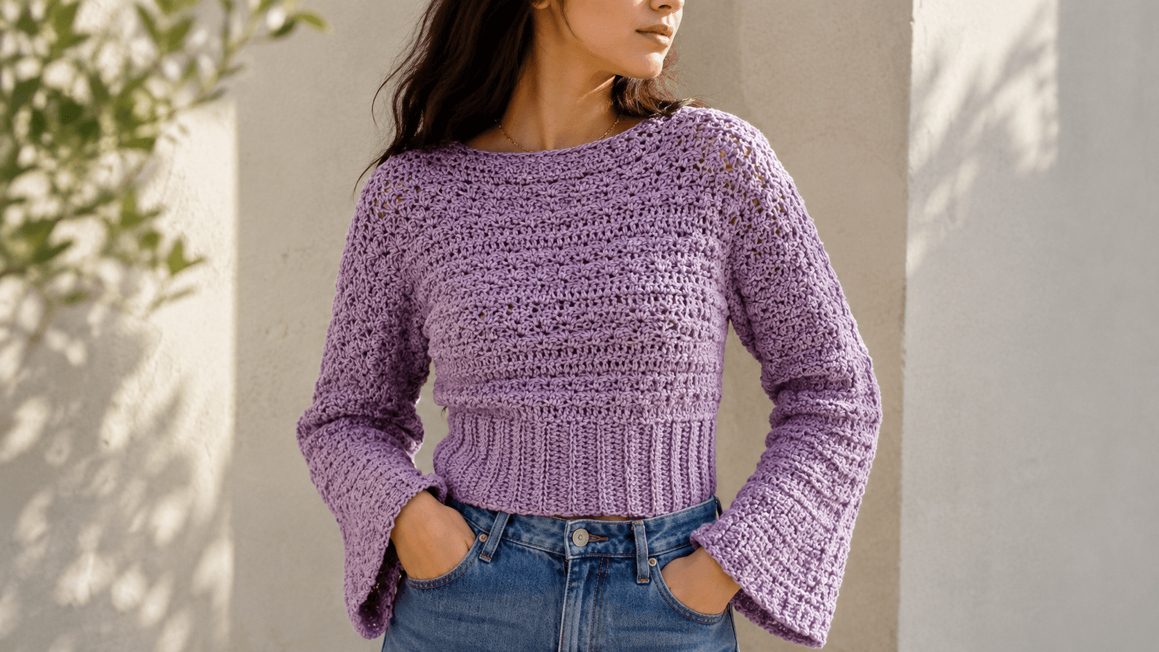 Woman wearing a lilac cropped crochet sweater with bell sleeves