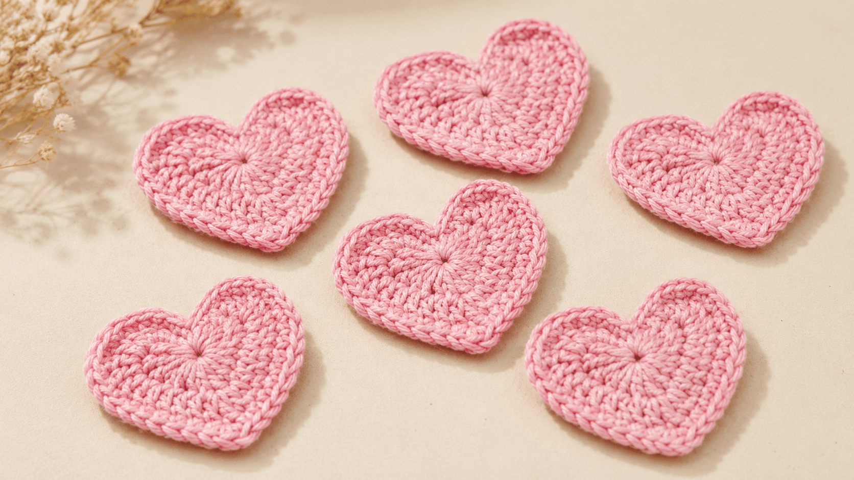 Six pink crochet hearts on a tan background