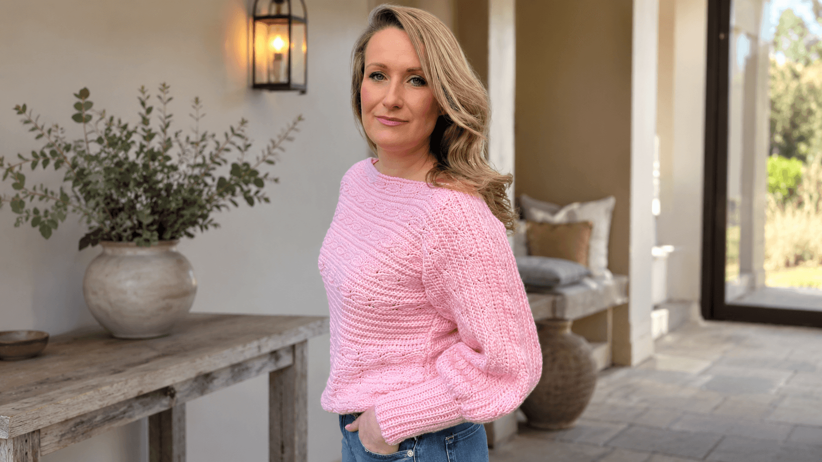Woman wearing a pink ribbed crochet crop sweater on a porch
