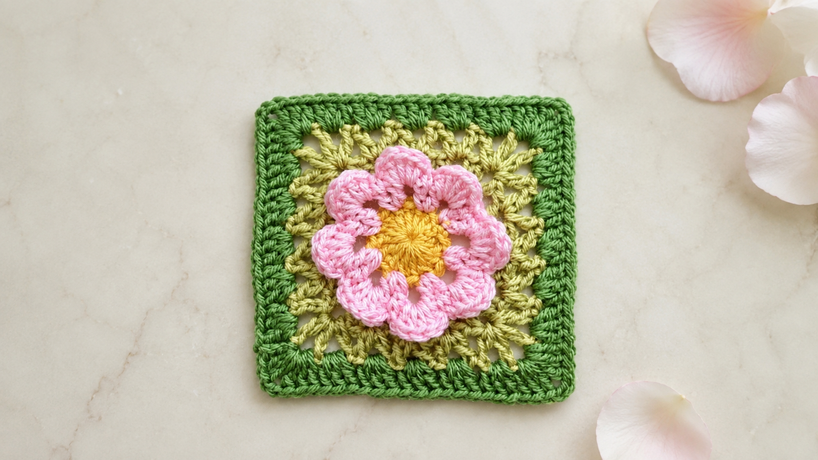 Pink crochet popcorn-stitch flower granny square on marble