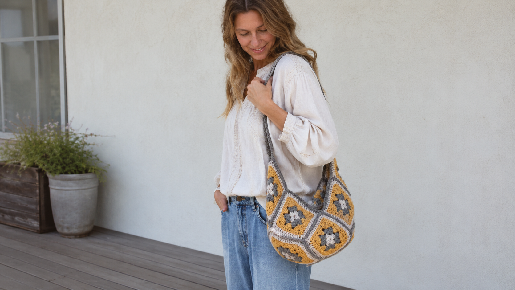 Mustard and gray granny square crochet bag carried on the shoulder