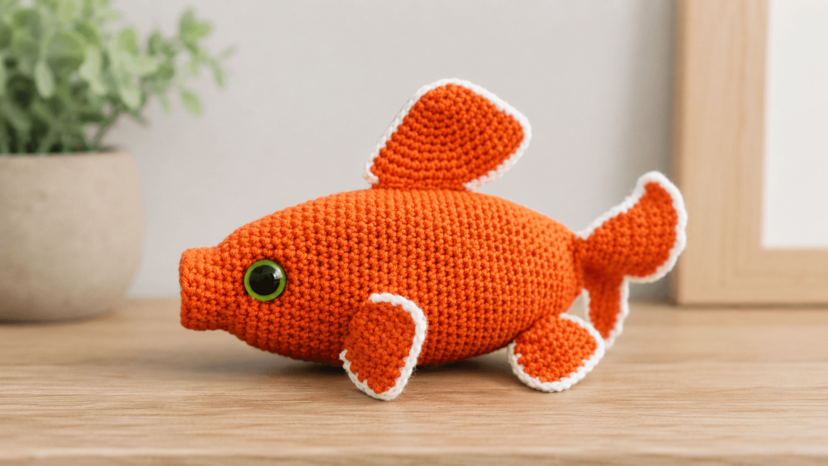 Orange crochet amigurumi fish with white-trimmed fins
