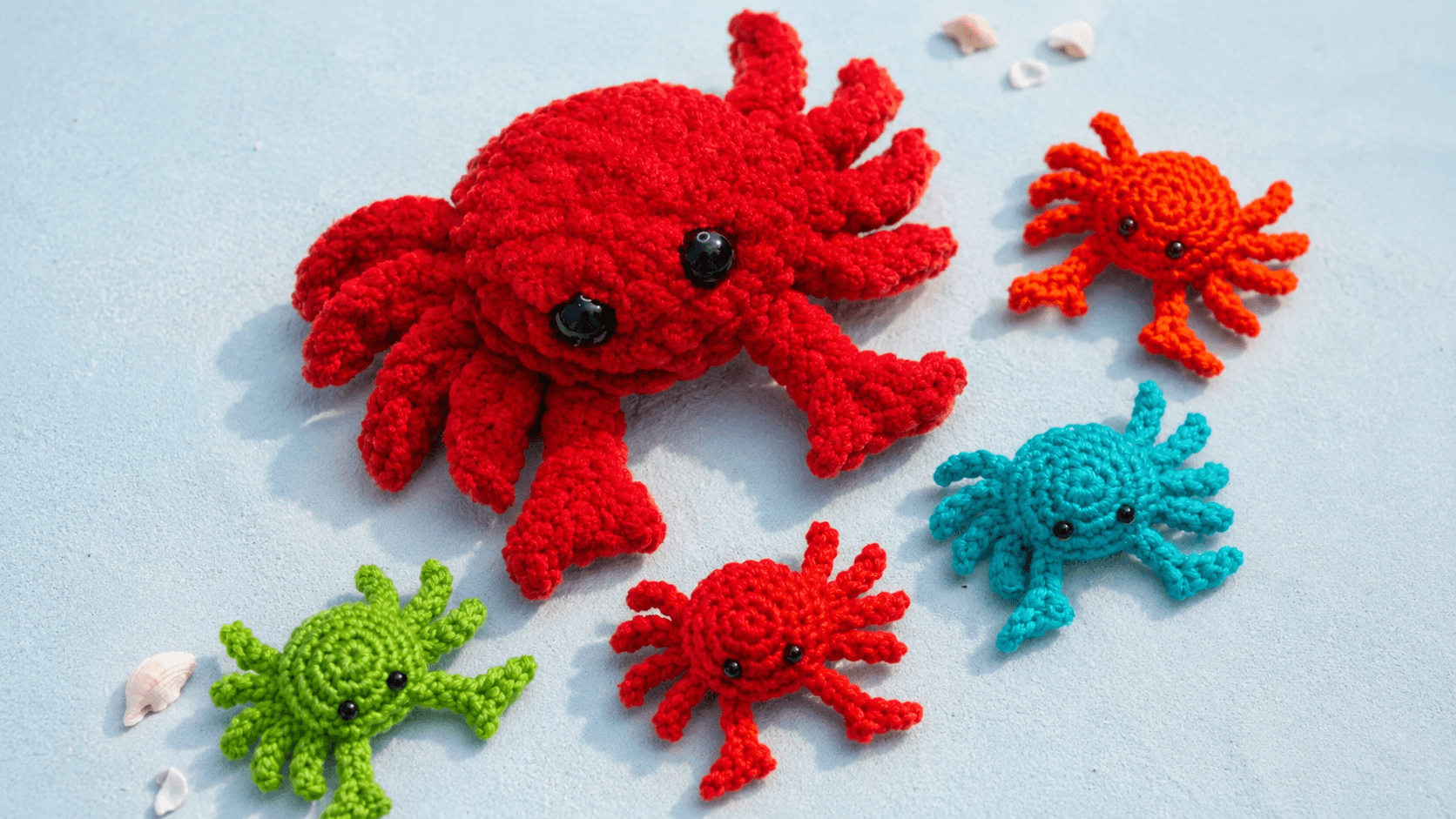Red crochet crab with smaller colorful crabs on a sandy background