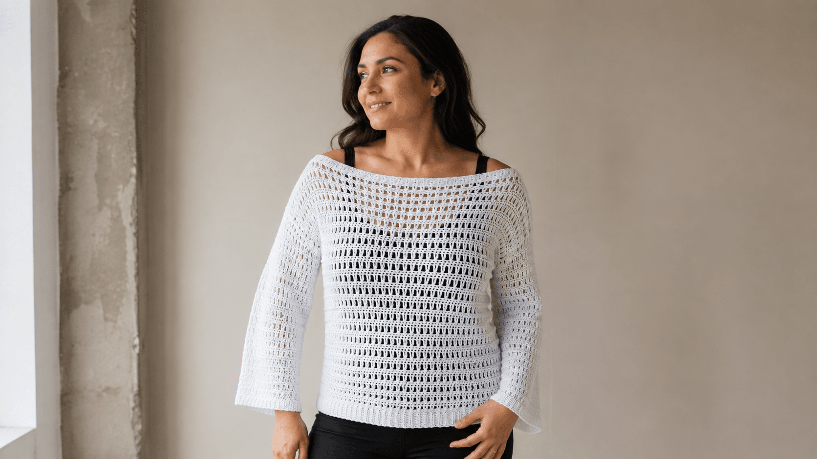 Woman wearing a white and gray off shoulder mesh crochet sweater