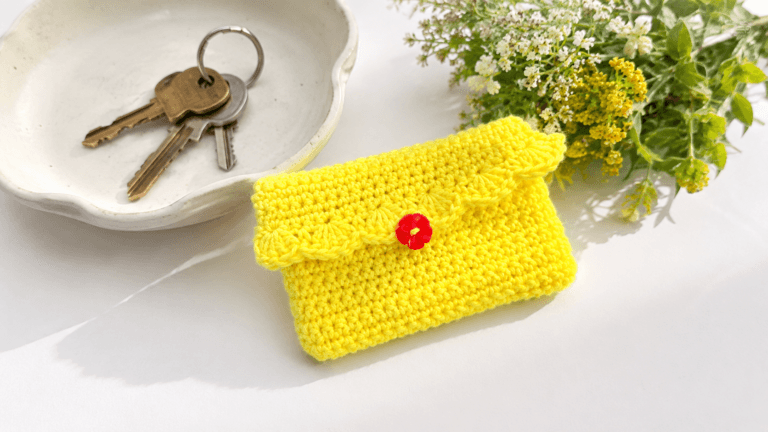 Yellow crochet card case with a scalloped flap and red flower button