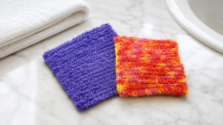 Purple and orange-red scrubby crochet dishcloths on a marble counter