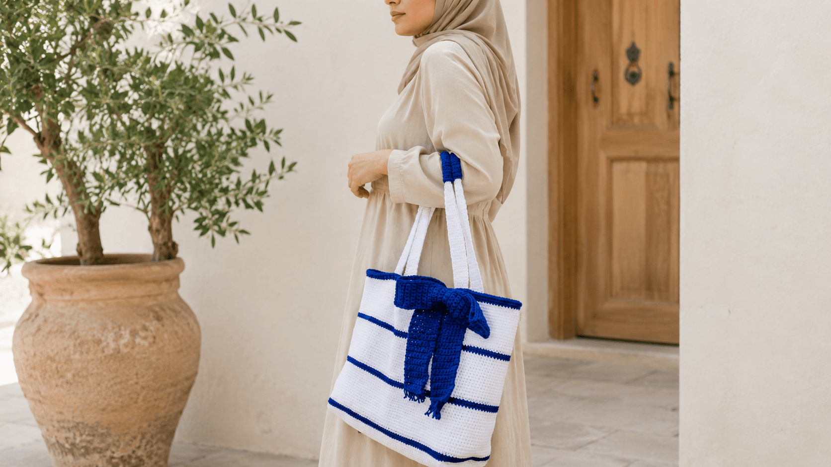 Woman carrying a navy and white striped crochet tote bag with a bow